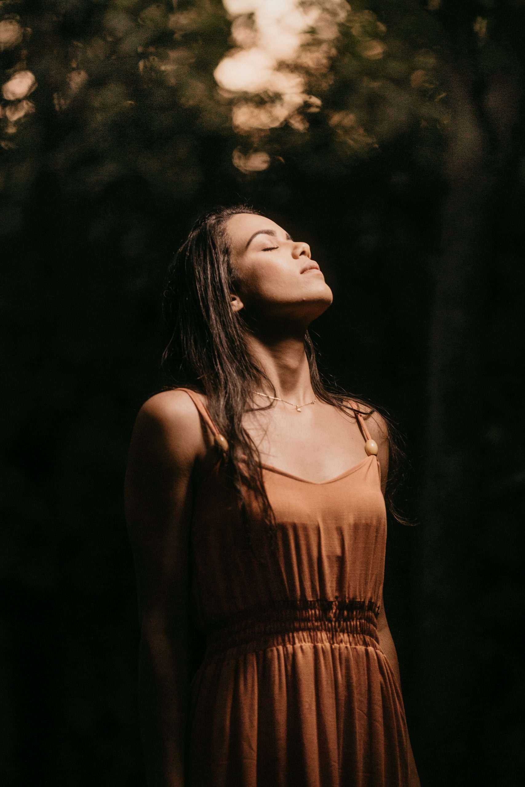 A tranquil portrait of a young woman enjoying a moment of relaxation outdoors at twilight.